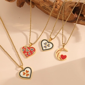 Détail de quatre colliers dorés avec pendentifs cœur et lune sur support bois
