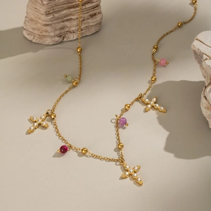 Detail of gold cross pendants with shiny crystals and colorful beads on a chain