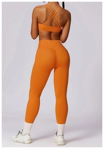 Detail view of bright orange yoga set featuring cross-back sports bra and high-waist leggings