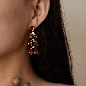 Detail of amber bead drop earrings with silver metal structure on a female model