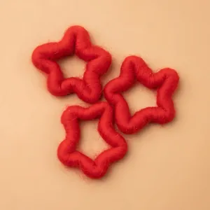 Three red wool felt star ornaments arranged on a beige background for Christmas decor