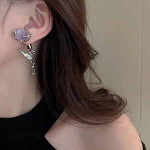Detail view of purple crystal rose earrings with silver thorn accents on a model