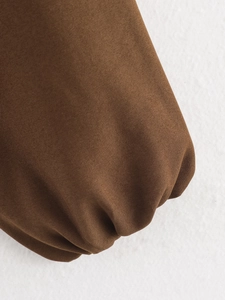 Gros plan d'une veste marron montrant la texture du sergé et les poignets élastiques