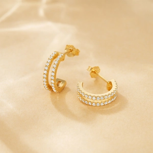 Detail of C-shaped gold-plated silver earrings with double rows of pavé cubic zirconia