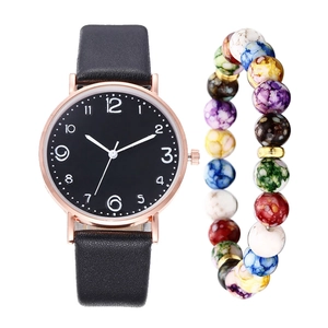 Detail shot of rose gold watch with black leather strap paired with colorful beaded bracelet