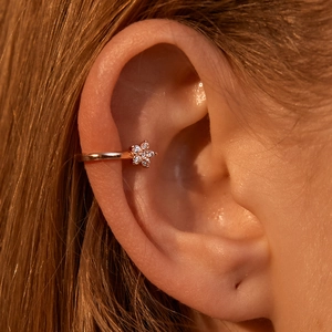 Rose gold five-petal flower ear cuff with sparkling diamonds on female ear