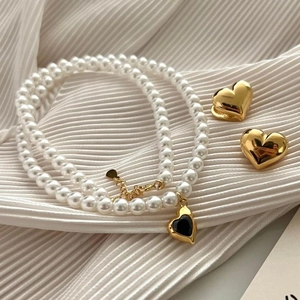 Close-up of elegant double-layer pearl necklace with black heart pendant and earrings