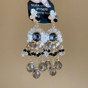 Dettaglio degli orecchini a fiore in argento con gemma blu e perline a goccia pendenti