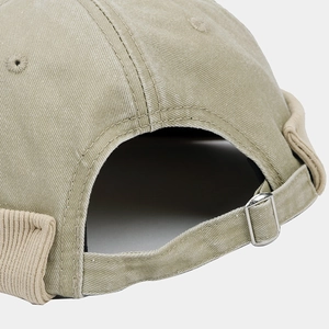 Detail of khaki cotton docker cap featuring adjustable metal buckle and fabric texture