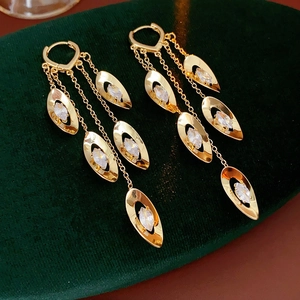 Détails des boucles d'oreilles à pompons dorés avec zircons sur velours vert