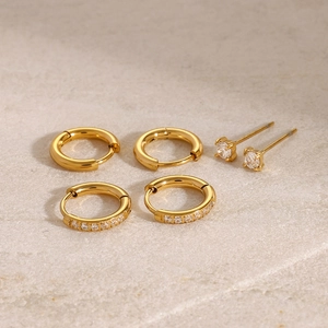 Detailed close-up of golden stainless steel earring set with zircon on marble background