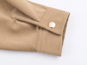 Gros plan détaillé du poignet kaki avec bouton doré poli et coutures de précision