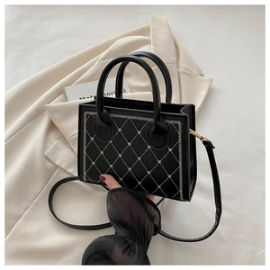 Detail of black quilted leather handbag with beige heart embroidery and dual handles