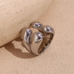 Gros plan d'une bague argentée sculpturale sur un fond de pierre beige texturée