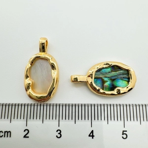 Macro shot of 18K gold plated oval pendants with white shell and abalone shell inlays
