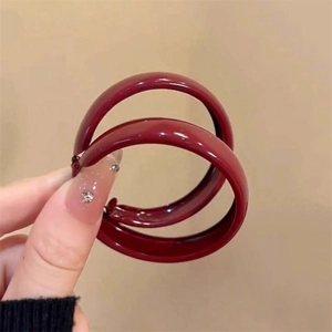 Macro detail of large dark red geometric hoop earrings with polished resin finish