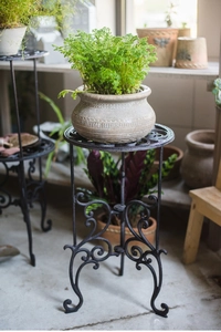 Détail d'un support de plante en fonte noire de style vintage avec des motifs ornementaux