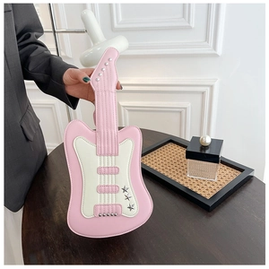 Detail of pink and white guitar shaped crossbody bag with star studs on a wooden table