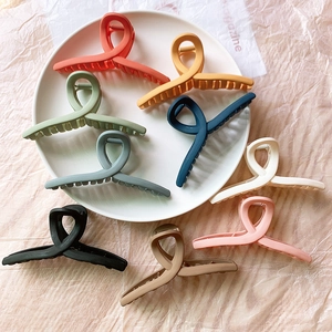 Vue détaillée de grandes pinces à cheveux mates en 9 couleurs sur une assiette blanche