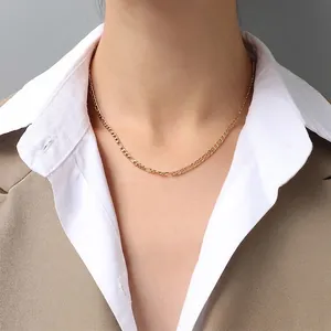 Detailed view of 3mm gold Figaro chain necklace worn by a model in a professional outfit
