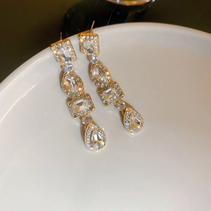 Macro shot of gold geometric earrings with square, oval, and teardrop crystals