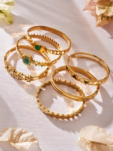 Detailed close-up of vintage gold bangle set with green enamel and zircon flowers