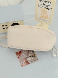 Detail view of a beige multifunctional travel makeup bag with top zipper and side handle strap