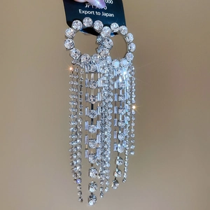Close-up of sparkling rhinestone tassel earrings with a round stud and silver finish