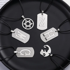 Detail of assorted silver metal pendants with hand-shaped and letter designs on black tray