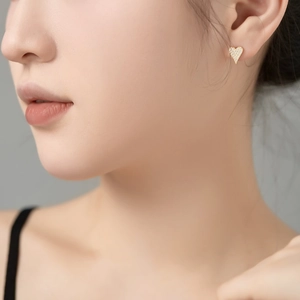Close-up of golden heart-shaped stud earrings with micro-paved sparkling cubic zirconia