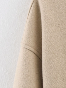 Detailed close-up of camel tweed fabric texture and high-quality stitching on jacket