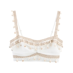 Detail of white bohemian bralette featuring delicate shell fringe and woven textures