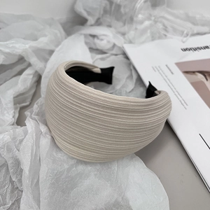 Close-up of beige striped fabric headband with anti-slip teeth on soft white fabric background