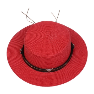 Red straw cowboy hat with wide brim, black leather band, and silver bull head detail