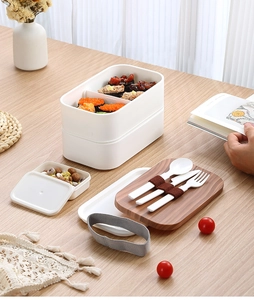 Detail view of double-layer white bento box with wood grain lid and cutlery set