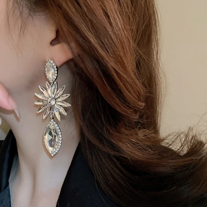 Close-up of sparkling flower drop earrings featuring teardrop crystals on model