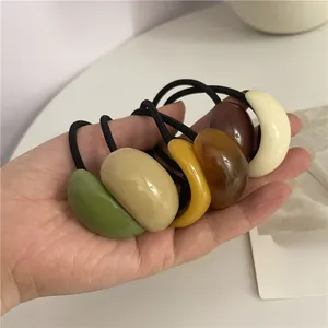 Close-up of flexible elastic hair ties with glossy resin pebble charms in earth tones