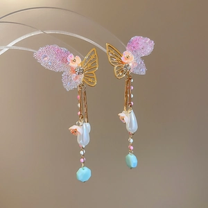 Detailed view of butterfly tassel earrings with pearls and pink floral accents