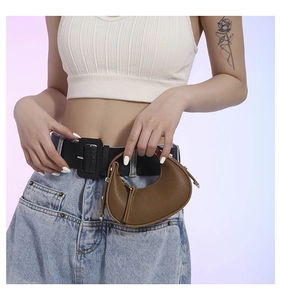 Detail view of a brown pebbled leather crescent mini bag worn as a stylish belt accessory