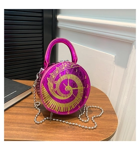 Detail view of pink round clock handbag with gold piano spiral design and chain strap