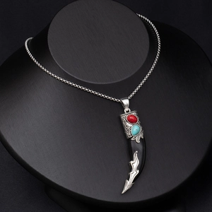 Detail of vintage faux wolf tooth pendant with red and turquoise stones on a silver chain