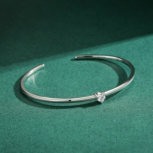 Elegant minimalist silver bangle with a sparkling round zircon on a green background