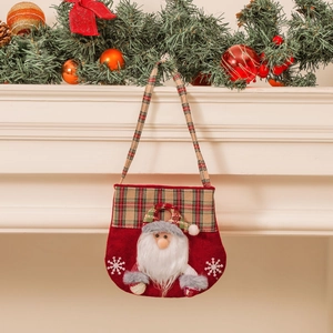 Christmas gift bag with 3D Santa Claus and classic red-green plaid handle on a fireplace