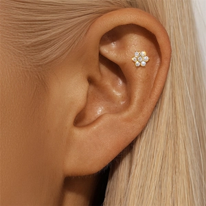 Macro detail of a 925 silver flower stud earring with gold plating and white diamonds