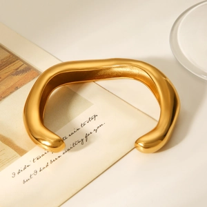 Macro shot of gold irregular wave pattern open bangle with a polished mirror finish