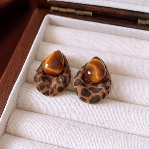Detailed macro view of teardrop resin earrings with leopard print and cat eye stone texture