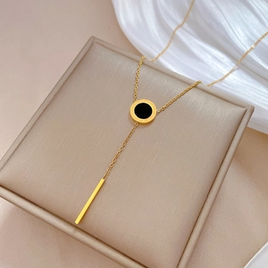 Detail of a gold titanium steel Y-necklace with black round pendant and long gold bar