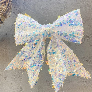 Large iridescent white sequin bow decoration with colorful reflective surface for holidays