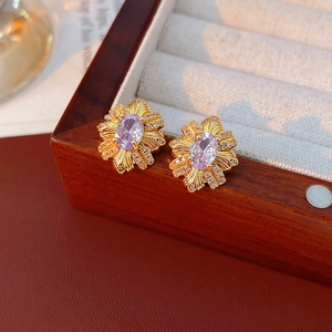 Gros plan de boucles d'oreilles vintage dorées avec pierre violette et zircons fins