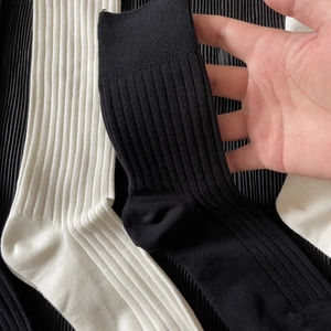 Pair of black and white ribbed JK mid-calf socks with high elastic vertical stripe texture